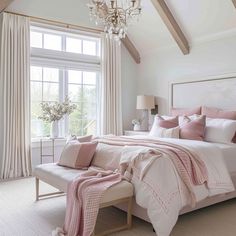 a bedroom with pink and white bedding, chandelier, windows, and curtains