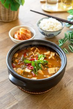 there is a bowl of soup on the table with rice and other dishes around it