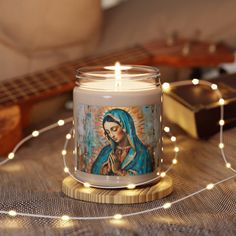 a candle that is sitting on top of a table with string lights and a guitar in the background