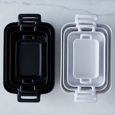 two black and white trays sitting next to each other on top of a table