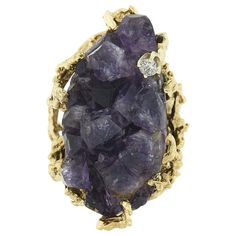 This magnificent vintage cocktail ring is crafted in solid 14k yellow gold and is set with a MASSIVE, rough, uncut amethyst crystal at its center. The incredible stone weighs approximately 30-50 carats, displaying a gorgeous medium to dark purple color that gives this very large ring such a rich look. The solitaire is uniquely prong set and elegantly sits at the center of the rings open, free-form, coral reef textured work that adorns the top and both sides of the shank, adding such a bold and u Vintage Cocktail Ring, Vintage Cocktail, Textured Ring, Large Ring, Diamond Crystal, Amethyst Crystal, Round Brilliant Cut Diamond, Cocktail Rings, Purple Color