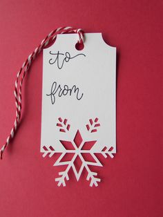 a white snowflake ornament hanging from a red string on a pink background