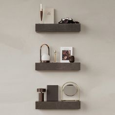 two floating shelves on the wall with various items in them and one holding a camera