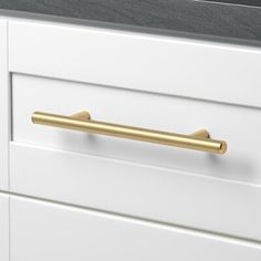 a white cabinet with brass handles and drawers