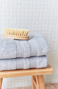 three towels stacked on top of each other with a wooden brush sitting on top of them