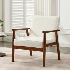 a white chair sitting on top of a rug next to a window