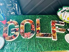 the word golf spelled out in letters on a green grass covered table with plates and forks