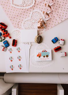 a table topped with lots of different types of toy vehicles and cards on top of it