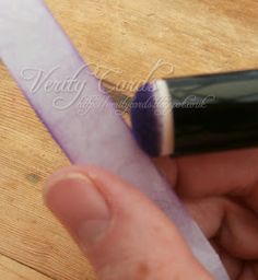 a person holding a purple toothbrush in their left hand and the other hand is pulling it up