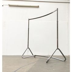 a metal sculpture sitting on top of a cement floor next to a white wall,