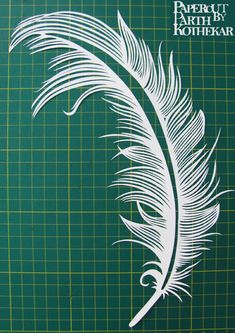 a close up of a white feather on a green cutting mat with the words oh