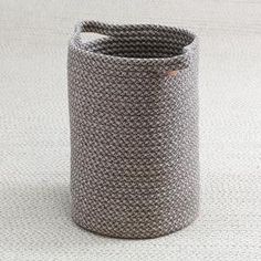 a gray basket sitting on top of a white carpet