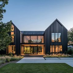 a large black house with lots of windows on it's sides and grass in the front yard