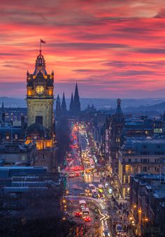 a city street filled with lots of traffic under a colorful sky