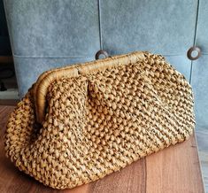 a woven purse sitting on top of a wooden table