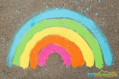 a rainbow drawn in chalk on the ground with blue, green, yellow and pink colors