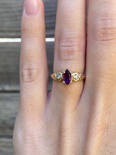 a woman's hand with a yellow gold ring and an amethyst stone