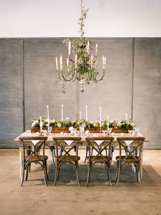 a dining room table with candles and flowers on the top is surrounded by greenery