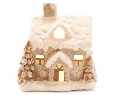 a lighted house with trees and snow on the roof is shown in front of a white background