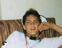 a young man sitting on top of a couch wearing headphones and a white shirt