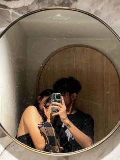 a man and woman taking a selfie in a round mirror on a marble wall