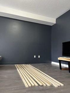 a flat screen tv sitting on top of a wooden floor next to a black table