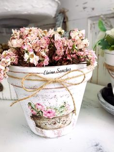 a potted plant with pink flowers tied to it's sides on a table