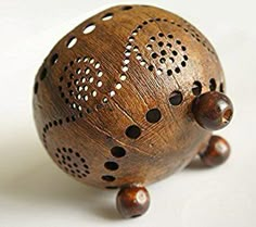 a decorative wooden object with holes in the top and sides, sitting on a white surface