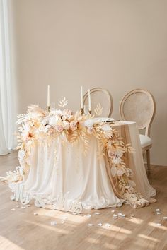 a table with flowers and candles on it in the middle of a room next to two chairs