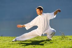 a man in white is doing yoga on the grass