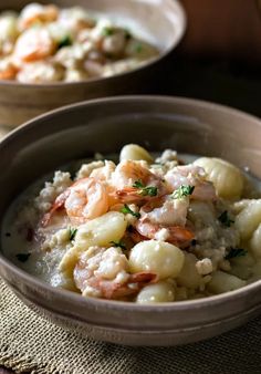 two bowls filled with shrimp and dumplings on top of a cloth covered placemat