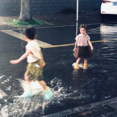 two children are playing in the water on a rainy day