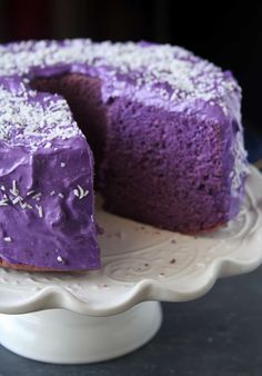 a purple cake with white sprinkles on it sitting on a platter