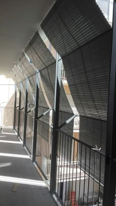 the sun is shining down on an empty hallway with metal railings and windows that are open