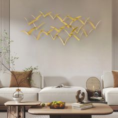 a living room filled with white couches and a coffee table in front of a wall mounted sculpture