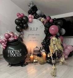 a halloween display with balloons, candles and a skeleton sitting in front of a sign