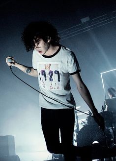 a man holding a microphone while standing on top of a stage