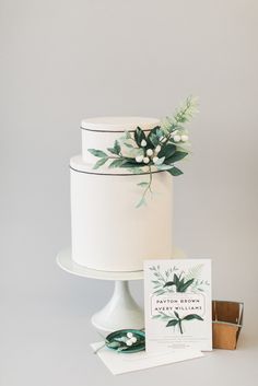 a white cake sitting on top of a table next to a card and some other items