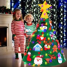 two children standing next to a christmas tree