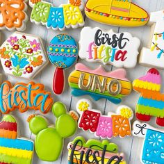 some decorated cookies are sitting on a white table top with the words fiesta written in different colors