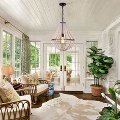 a living room filled with lots of furniture and plants on top of a hard wood floor