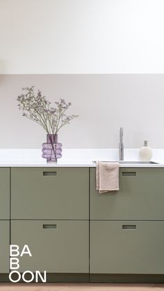 a kitchen with green cabinets and white counter tops