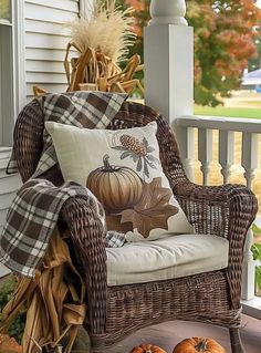 a wicker chair sitting on a porch with fall decorations and pumpkins around it