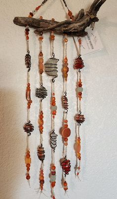 a wind chime hanging on the wall next to a piece of drift wood and beads