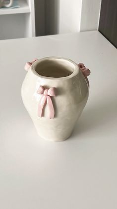 a white vase sitting on top of a table covered in pink ribboned bow decorations