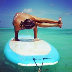 a woman is standing on a surfboard in the clear blue water, with her legs spread out