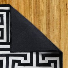 a piece of black and white tile sitting on top of a wooden floor