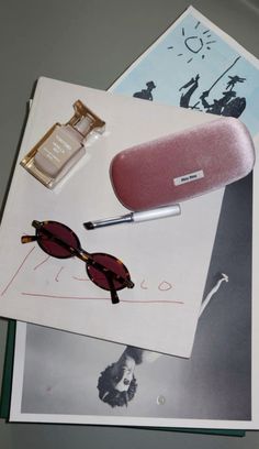 an assortment of items on top of a table including sunglasses, lipstick and perfume bottle