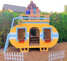 a group of people standing on top of a yellow and blue house shaped like a boat