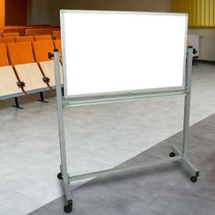 an empty whiteboard is in the middle of a lecture hall with rows of chairs